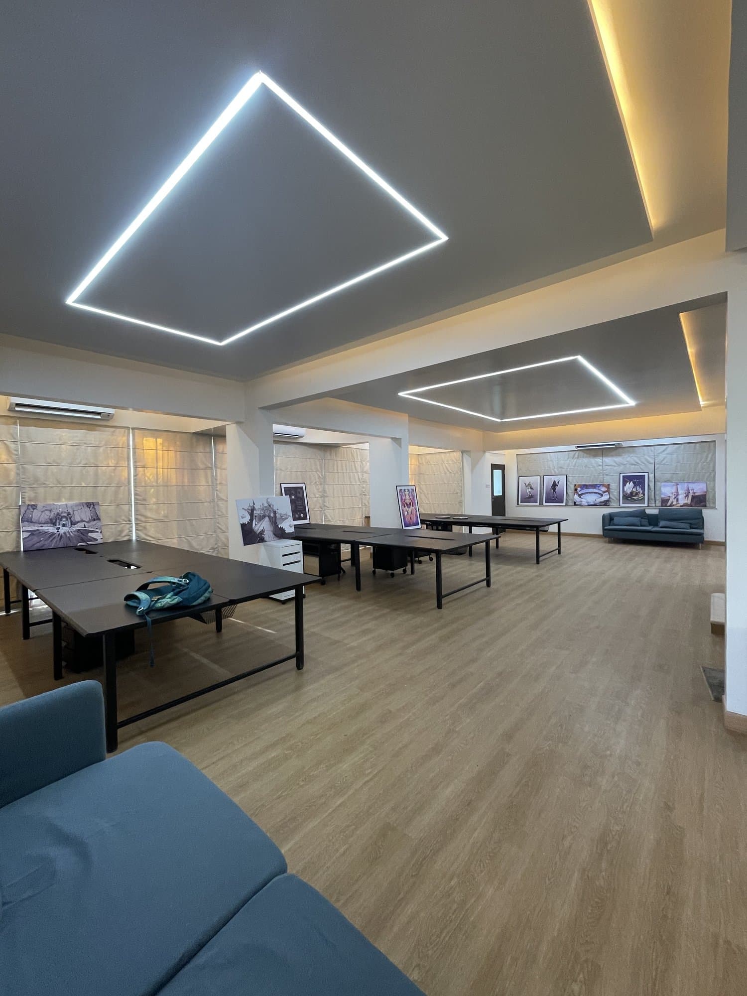 The transformed entry hall — now an open-plan office lounge with wood flooring and a backlit ceiling feature
