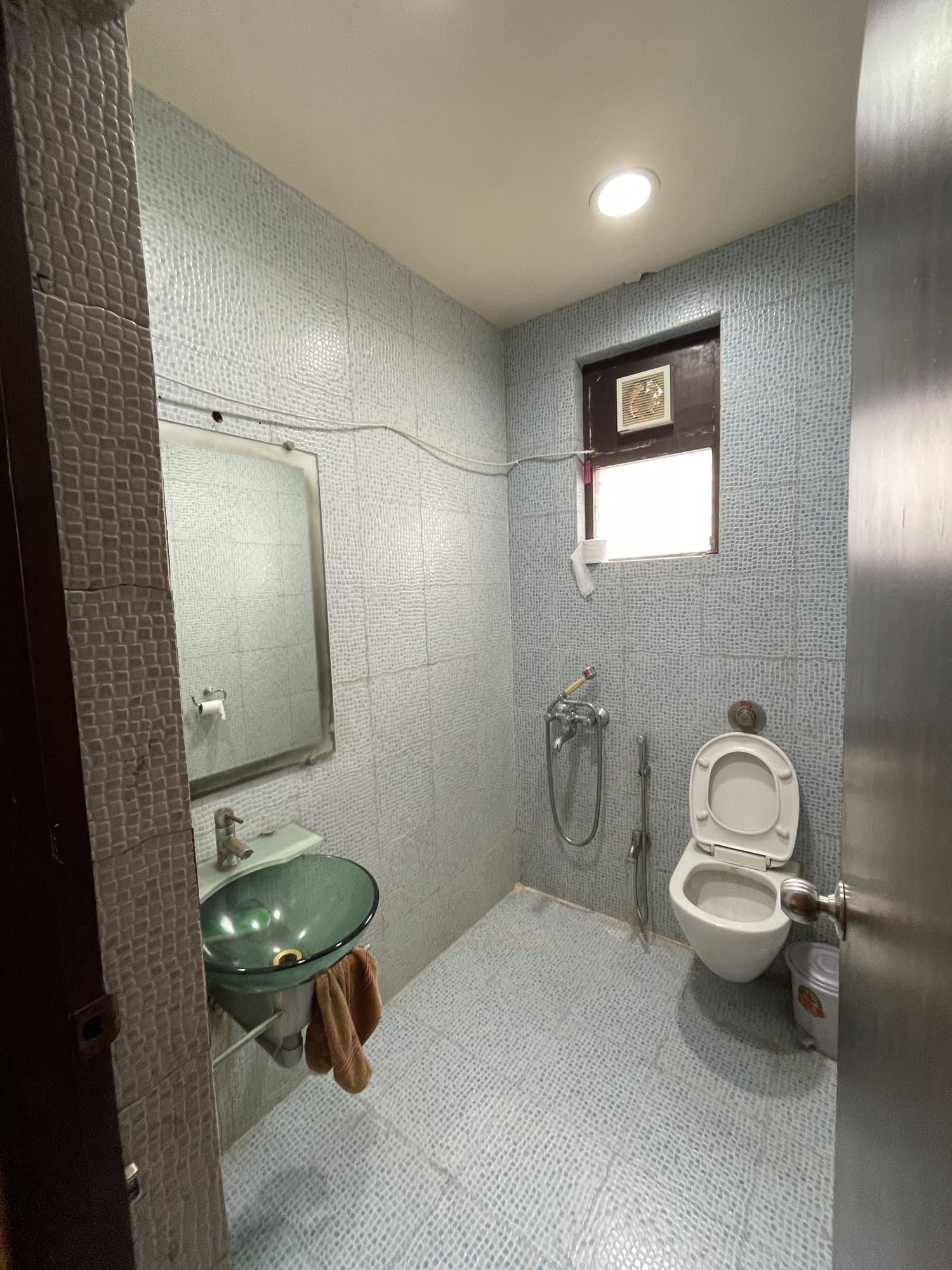 The existing bathroom before renovation — plain tiling, a pedestal-style layout and a small window