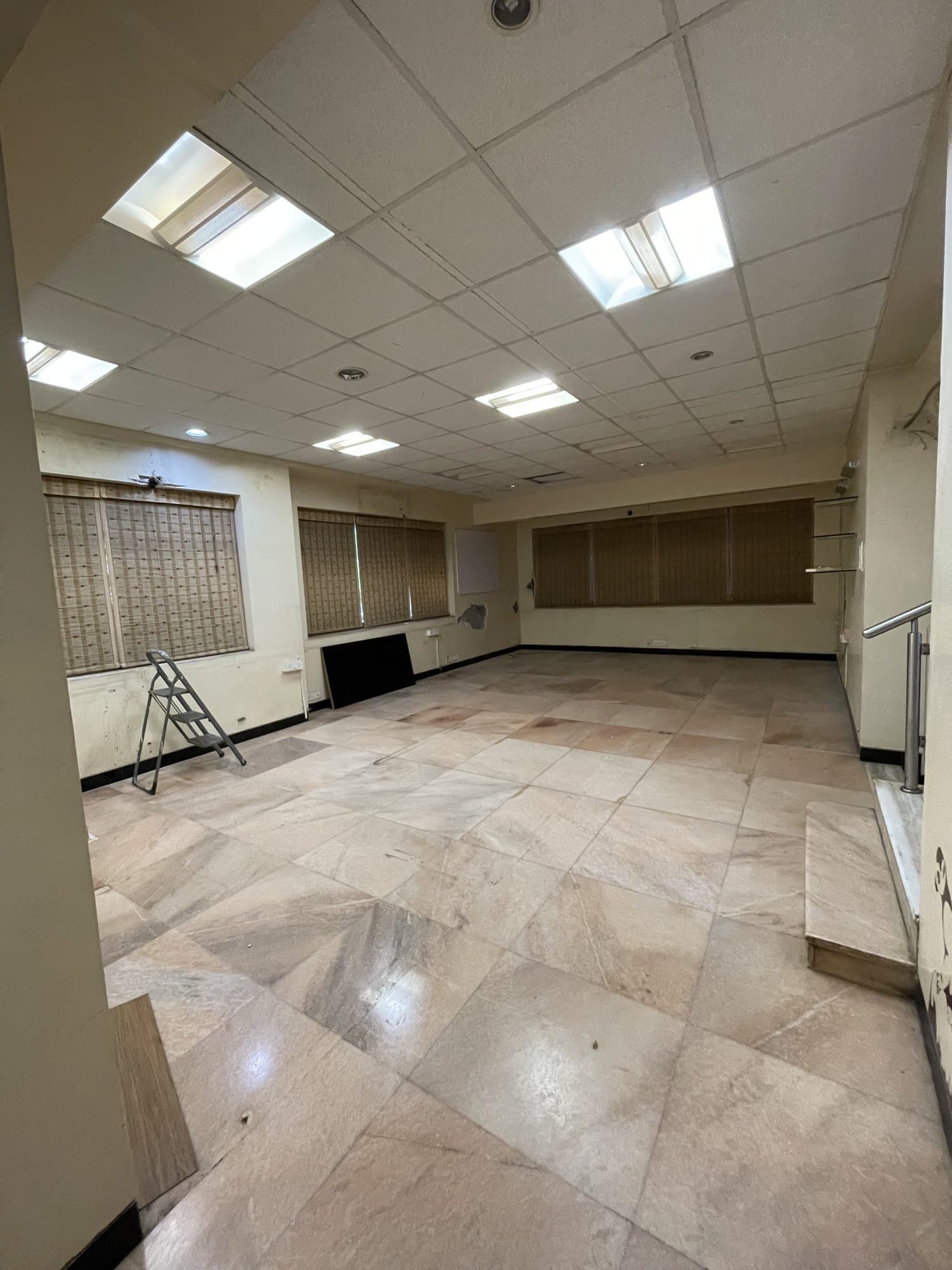 The existing entry hall before renovation — empty, with dated ceiling tiles and marble flooring